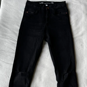 Svarta jeans med hål - Svarta jeans från Lab Industries med slitna detaljer vid knäna. Storlek: 158. Fraktar inom 24h!