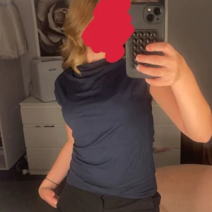 Mörkblå tröja  - Säljer en stilren mörkblå topp med draperad halsringning. Perfekt för dig som gillar minimalistisk och modern stil. Materialet känns mjukt och följsamt mot huden.