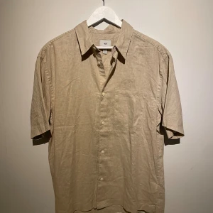 Beige linneskjorta från H&M - Snygg beige skjorta från H&M i relaxed fit, tillverkad i linne. 