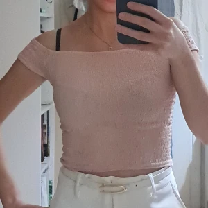 Ljusrosa offshoulder topp H&M Divided - Supersöt ljusrosa croppad topp från H&M Divided. Modellen är offshoulder med korta ärmar och smockad struktur som ger en tight och bekväm passform. Perfekt till jeans eller kjol för en trendig look.