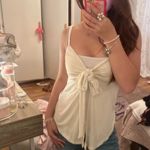 Vit linnetopp med knyt från Gina Tricot - Supersöt vit linnetopp från Gina Tricot i storlek XS. Toppen har smala axelband och en stor knytning framtill som ger en unik och trendig look. Perfekt till jeans eller kjol för en fräsch sommarstil.