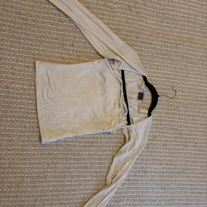 Vit långärmad topp från Gina Tricot - Säljer en enkel och stilren vit långärmad topp från Gina Tricot. Toppen har en figurnära passform och är tillverkad i mjuk bomull, perfekt att matcha med jeans eller kjol. Klassisk rund halsringning och slät yta.