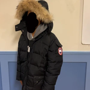 Svart Canada Goose dunjacka med päls - passar dig bra som är 156-160 cm  Säljer en svart dunjacka från Canada Goose med stor huva och snygg pälsdetalj. Jackan har klassisk patch på ärmen, flera fickor och dragkedja framtill. Perfekt för dig som vill ha en varm och stilren vinterjacka med exklusiv känsla. Sönder i höger vänster ficka och lite sönder i luvan