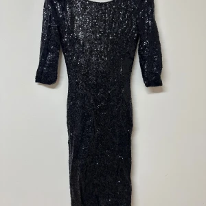 Svart glittrig klänning från ISKA London - Supersnygg svart paljettklänning från ISKA London med trekvartsärm och öppen rygg. Klänningen är figurnära och har en glittrig yta som verkligen sticker ut. Perfekt för dig som vill glänsa och göra intryck, även perfekt till bröllop eller andra festligheter som jul och nyår! Säljes i storlek 38. Endast använd en gång!✨🖤