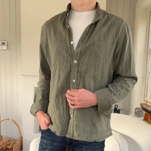 Olivgrön skjorta från Morris Stockholm - Olivgrön skjorta från Morris Stockholm i storlek L. Skjortan har klassisk krage, knappar framtill och långa ärmar. Materialet är mjukt och känns som bomull, perfekt för en chill och stilren look. Passformen är normal och färgen är diskret grön.