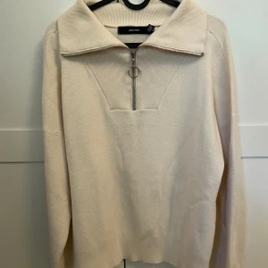 Beige stickad tröja från Vero Moda - Säljer en beige stickad tröja från Vero Moda med hög krage och snygg half zip-dragkedja med ringdetalj. Tröjan har lång ärm och en loose passform, perfekt för lager-på-lager och chill vibes.