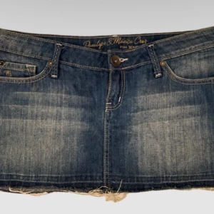 Blå jeanskjol från Penelope & Monica Cruz - Snygg blå jeanskjol med rå kant och slitna detaljer från Penelope & Monica Cruz. Klassisk femficksmodell med broderad bakficka och knappstängning framtill. Den är i väldigt bra skick och inte så använd. 