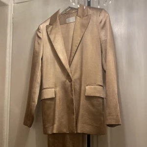 Guld satin kostym från Mango - Jättefin satin kostym set från Mango. Byxor ingår som är raka. Förekommer trådar (kolla bilderna) 
