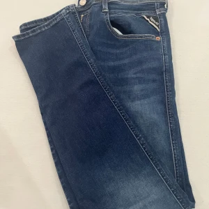 Replay jeans blå - Säljer ett par blå Replay jeans i slim, snygga kontrastsömmar och diskret Replay-logga vid fickan. Materialet är stretchigt och bekvämt, perfekt för dig som gillar en smalare passform.