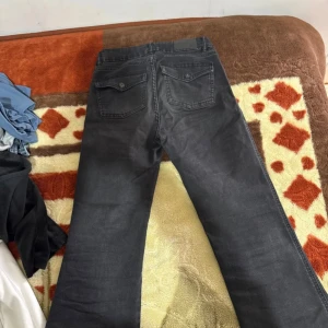 Bootcut jeans från 157, svart - Svarta bootcut jeans från 157 med klassisk femficksdesign och knappgylf. Modellen heter 90's Boot Star och har en snygg, något utsvängd passform. Jeansen är tillverkade i ett mjukt denimtyg som ger en skön känsla och cool look.