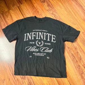 Svart oversized t-shirt FSBN XXS - Svart oversized t-shirt från FSBN med tryck i vitt framtill: 'INFINITE Vibes Club New York'. Klassisk rund hals och korta ärmar. Skön bomullskvalitet och loose fit för en avslappnad streetstyle.