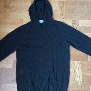 Svart hoodie i kashmir från Davida - Svart hoodie från Davida i storlek L, tillverkad i mjuk kashmir. Tröjan har huva, långa ärmar och en klassisk, enkel design utan mönster eller detaljer. Perfekt för dig som gillar stilrena och bekväma plagg med lyxig känsla. Den är väldigt lite använd och säljer då den inte kommer till använding längre. Den sitter som en större M eller liten L. Hör av er vid fler frågor. Pris ej hugget i sten