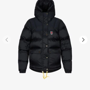 Svart dunjacka från Fjällräven - Svart dunjacka från Fjällräven med huva och gul snörning nedtill.  Är en S men har använt denna stora mysiga jacka flera vintrar. Super bra skick fortfarande! 