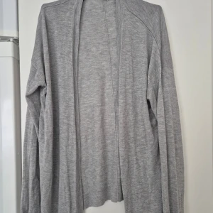 Kofta - Enkel och stilren grå kofta i mjukt material från H&M. Modellen är öppen framtill utan knappar och har lång ärm. Perfekt att slänga på sig över en t-shirt eller linne för en chill look.