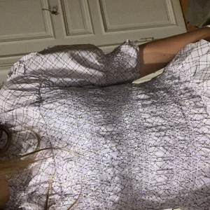 Ljuslila rutig blus från Monki - Supersöt ljuslila blus från Monki med rutigt mönster och volangdetaljer vid hals och nederkant. Blusen har smockad midja och trekvartsärmar med puff. Perfekt för dig som gillar romantisk och trendig stil.