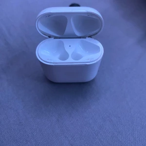 AirPods 2 laddningsetui - Original Apple AirPods 2 laddningsetui. Fungerar bra, men har synligt smuts och slitage runt insidan av locket och hörlursfacken. Perfekt som reserv eller ersättning. Hörlurar ingår ej.