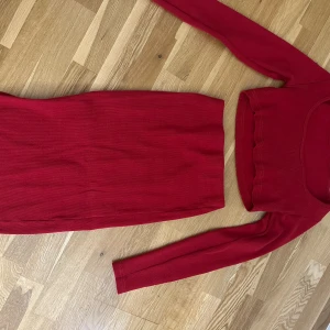 Röd långärmad kjol & tröja sett XS - Röd, tight långärmad tröja och kjol i ribbat material. Settet är figurnära och har en enkel, stilren design utan mönster. Tillverkad i stretchigt tyg med 95% nylon och 5% spandex för en bekväm passform.