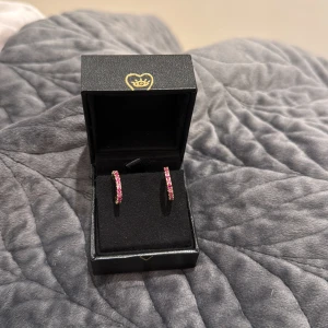 Rosa glittriga örhängen i guld - Säljer ett par snygga örhängen med rosa glittrande stenar runt hela ringen. De är små hoops. Perfekta för dig som gillar färg och bling!