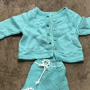 Turkos stickad kofta med knappar - Turkos stickad kofta med rund hals och dekorativa stickade detaljer. Koftan har lång ärm och stängs med fem matchande knappar framtill. Mjuk och skön känsla, perfekt för att hålla värmen under kyliga dagar. Snygg struktur och klassisk look.