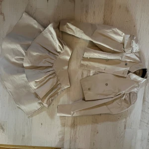 Beige croppad jacka och kjol set från AVAVAV - AVAVAV- Set  Använd 1-2 gånger  Cream-färgad med guld skimmer  Saknas en knapp  Pris kan diskuteras   AVAVAV- Set used 1-2 times  Cream colored with gold shimmer one button missing  Prize can be negotiated