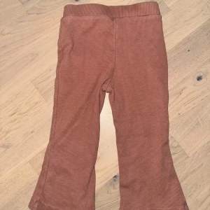 Rostbruna ribbade manchesterbyxor Bruna byxor, storlek 90 - Säljer ett par rostbruna manchesterbyxor med ribbad struktur och utsvängda ben. Byxorna har en mjuk midja och är perfekta för dig som gillar retrostil och bekväma plagg. Passar dig som vill ha en cool och avslappnad look.Bruna byxor med utsvängda ben.