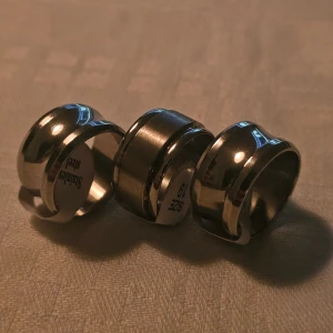 Breda ringar i rostfritt stål, storlek 19 - Tre breda ringar i silverfärgat rostfritt stål, storlek 19. Ringarna har en modern och stilren design med både blanka och matta ytor som ger en cool kontrast. Alla är I Rostfritt stål och ca 19 mm