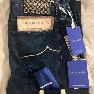 Limited Jacob Cohën mørkeblå custom bard - Originalpris: 820€ Kjøpt i milano på custom jacob cohën butikk. Med certilogo, autentisitetsbevis. 98% cotton, 2% elastan Selvom det fortsatt er et dyrt kjøp, vil denne buksen vare deg ut livet, siden den til og med kommer med samme tråd som ble brukt, så du kan sy den igjen. Så dette er en veldig god deal Jacob cohen gir deg en eksklusiv og luksuriøs følelse med alle de små detaljene. Den vakre mørkeblå fargen passer til hva som helst og gir deg et premium preg i antrekket ditt.