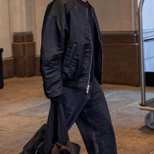 Svart bomberjacka från Our Legacy - Svart bomberjacka från Our Legacy med klassisk ribbad krage och muddar. Jackan har dragkedja framtill, fickor med knapp och en extra ficka med dragkedja på ärmen. Jackan har en loose passform som är chill och enkel att styla. Pris kan diskuteras! Bilden är bara till för att visualisera passformen. 