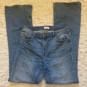 Blå bootcut jeans från Lindex - Snygga blå jeans från Lindex med klassisk femficksdesign och bootcut-ben.  Välanvända men i gott skick. Jeansen har normal passform och är tillverkade i ett mjukt denimtyg med lätt tvättad look. Perfekta att styla med sneakers eller boots. Jag säljer dessa eftersom de är för stora för mig.