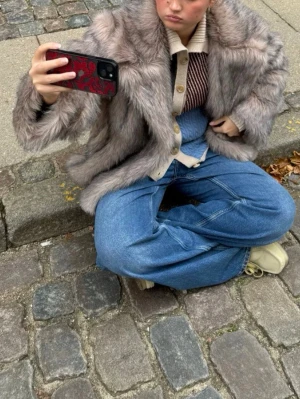 Grå pälsjacka med oversized passform - Säljer en fluffig och oversized grå pälsjacka med bred krage. Jackan har en cool, lite boxig siluett och är tillverkad i fuskpäls som känns supermjuk. Oanvänd säljer då jag inte hann lämna tillbaka storleken är xs/s nypris 1136kr