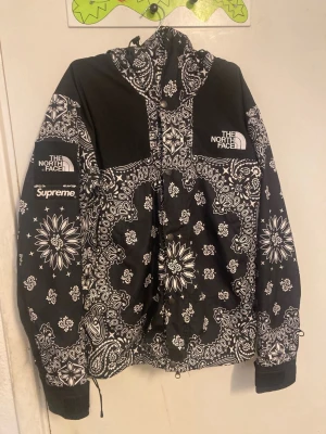 Supreme x The North Face 2014 paisley windbreaker - Supreme x The North Face Bandana Mountain Jacket – Black (M) – knappt använd, som ny. Har bara samlat damm i garderoben Storlek: Medium Säljer min extremt sällsynta Supreme x TNF Bandana Mountain Jacket i svart. Modellen är nästan omöjlig att få tag på och är ett av de mest eftertraktade samarbetena från Supreme x The North Face. Jackan är i perfekt skick utan defekter   Denna modell går för mellan 3 000–4 000 USD på StockX och ökar bara i värde. Perfekt för samlare eller dig som vill rocka ett 