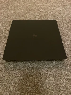 PlayStation 4 Slim - Snygg och stilren PlayStation 4 Slim i svart. Konsolen ser ut att vara i gott skick utan synliga repor eller skador. Perfekt för dig som vill spela de senaste spelen med snabb prestanda och kompakt design. Inga tillbehör syns på bilderna.