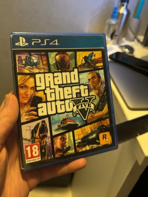 Grand Theft Auto V (GTA V) PS4 - Grand Theft Auto V till PlayStation 4. Omslaget och fodralet ser ut att vara i gott skick. Ett populärt actionspel med öppen värld och många speltimmar. PEGI 18-märkt.