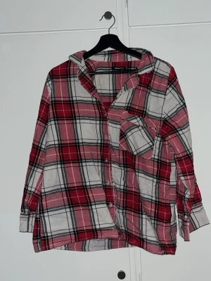 Rutig röd skjorta från Gina Tricot - Säljer en rutig skjorta från Gina Tricot i rött, vitt och svart. Skjortan har klassisk krage, långa ärmar med knapp vid manschetten och en bröstficka. Perfekt för dig som gillar avslappnad stil. Är i XS, men är oversized. Andvänd ett par gånger 