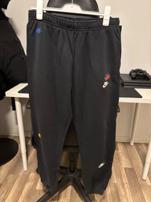 Svarta mjukisbyxor från Nike XL - Svarta mjukisbyxor från Nike i storlek XL. Flera broderade Nike-loggor i olika färger och stilar på benen. Används ej därav till salu! Pm vid fler frågor!