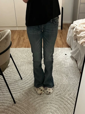 Bootcut jeans från Cheap Monday - Säljer ett par blå bootcut jeans från Cheap Monday i storlek 26/32. Jeansen har klassisk femficksdesign och är tillverkade i en mix av bomull, polyester och elastan för skön stretch. Snygg mörkblå tvätt och orange detaljer vid midjan.