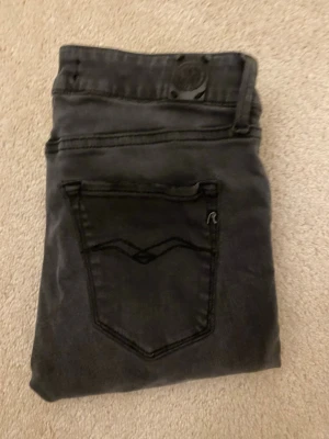 Replay svarta skinny jeans 27/32 - Säljer ett par svarta Replay jeans i modellen skinny med klassisk femficksdesign och snygga detaljer på bakfickorna. Jeansen har normal midja och är tillverkade i stretchig bomullsmix för skön passform. Perfekta till sneakers eller boots.