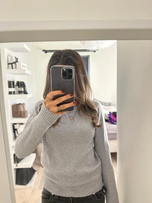 Grå stickad tröja från VILA - Snygg grå stickad tröja från VILA i storlek XS. Tröjan har rund hals, ribbade muddar vid ärmslut och nederkant samt långärmad passform. Perfekt för lager-på-lager och enkel att matcha med jeans eller kjol.