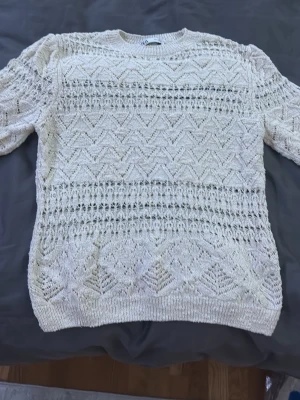 Vit stickad tröja från Zara, M - Säljer en vit stickad tröja från Zara i storlek M. Tröjan har korta ärmar och ett snyggt hålmönster med geometriska detaljer. Rund halsringning och ribbad kant nedtill och vid ärmslut. Perfekt för dig som gillar en ljus och fräsch look.