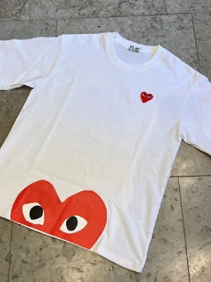 Vit Cdg play t-shirt - Säljer en vit t-shirt från Cdg Play med deras ikoniska tryck och logga framtill. Storlek M och är i väldigt bra skick, fraktas inom 24h✅