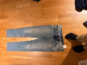 Replay Wallis ljusblå jeans - Säljer ett par Replay Wallis jeans i ljusblå tvätt med snygga slitningar och klassiska fem fickor. Jeansen har raka ben och normal passform, med detaljerade sömmar och Replay-märke bak. Perfekt för dig som gillar stilrena och bekväma jeans.