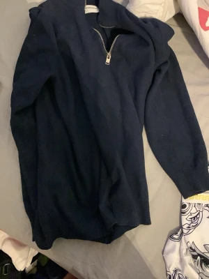 Marinblå stickad tröja Lindbergh - Snygg marinblå stickad tröja från Lindbergh med half zip-dragkedja i halsen. Tröjan har långärmade ärmar och en klassisk, lite loose passform. Perfekt för dig som gillar stilrena och enkla plagg med en modern touch. Priset kan sänkas vid snabb affär