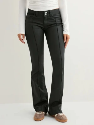 Coated low waist stitch jeans  - Säljer ett par svarta bootcut byxor med pressveck framtill och dubbla knappar i midjan. Byxorna har fickor både fram och bak samt bälteshällor. Materialet har en lätt glansig finish som ger en snygg look. Beställde fel storlek, aldrig använda bara testade. Pris kan diskuteras