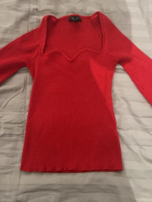 Röd glitter topp från Amisu -  Säljer en röd glittrig topp från Amisu med långärmad design och snygg vågig halsringning. Modellen är slim och ribbad, vilket ger en schysst passform. Perfekt för dig som gillar färgstarka och stilrena plagg. Den är är väldigt stretchig💕