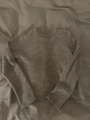 Beige stickad tröja från ONLY - Säljer en beige stickad tröja från ONLY i storlek S. Tröjan har ett vågigt mönster med små hål och ribbade muddar vid ärmslut och nederkant. Använd 1 gång 🤍