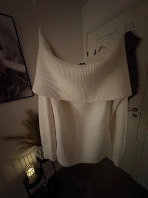 Offshoulder stickad tröja från Bikbok - Säljer en krämvit stickad tröja från Bikbok i storlek XS, som aldrig är använd. Tröjan har en bred offshoulder-krage och är ganska lång. Nypris: 600 kr