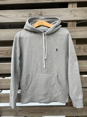 Ralph Lauren Grå Hoodie  - Schysst grå Ralph Lauren Hoodie. Storlek M men passar som en Större S eller som en M. I bra skick, finns en mindre synbar fläck på undersidan av ena armen (bild 2), i övrigt bra skick men inte lika mjuk som när den var ny längre. Hör gärna av er vid funderingar🙌 Perfekt för vintern☃️🥶