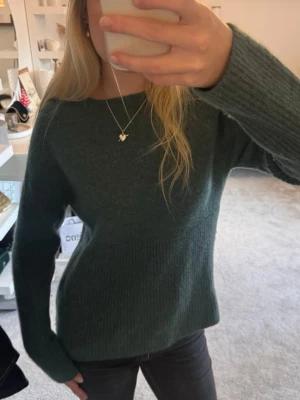 Mörkgrön stickad tröja - Säljer en mörkgrön stickad tröja med rund hals och långa ärmar. Tröjan har en ribbad struktur nedtill och vid ärmsluten, vilket ger en snygg och enkel look. Den är aldrig använd och i super bra skick! 