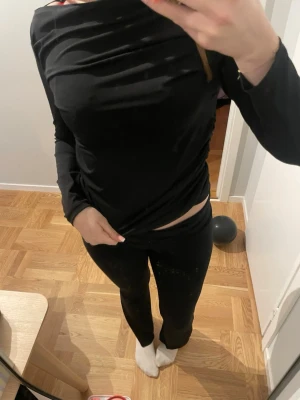 Svart långärmad topp från Vero Moda - Säljer en svart långärmad topp från Vero Moda i storlek M. Toppen har snygga rynkade detaljer på sidan och är figurnära med en stilren, enkel design. Materialet är mjukt och stretchigt, perfekt för att skapa en cool look.