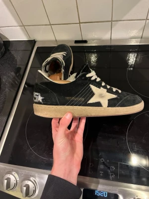 Golden goose skor - Golden Goose sneakers i svart mocka med vit stjärndetalj på sidan och broderad text på hälen. Skorna är i modellen ballstar som kommer med en stilren sko.